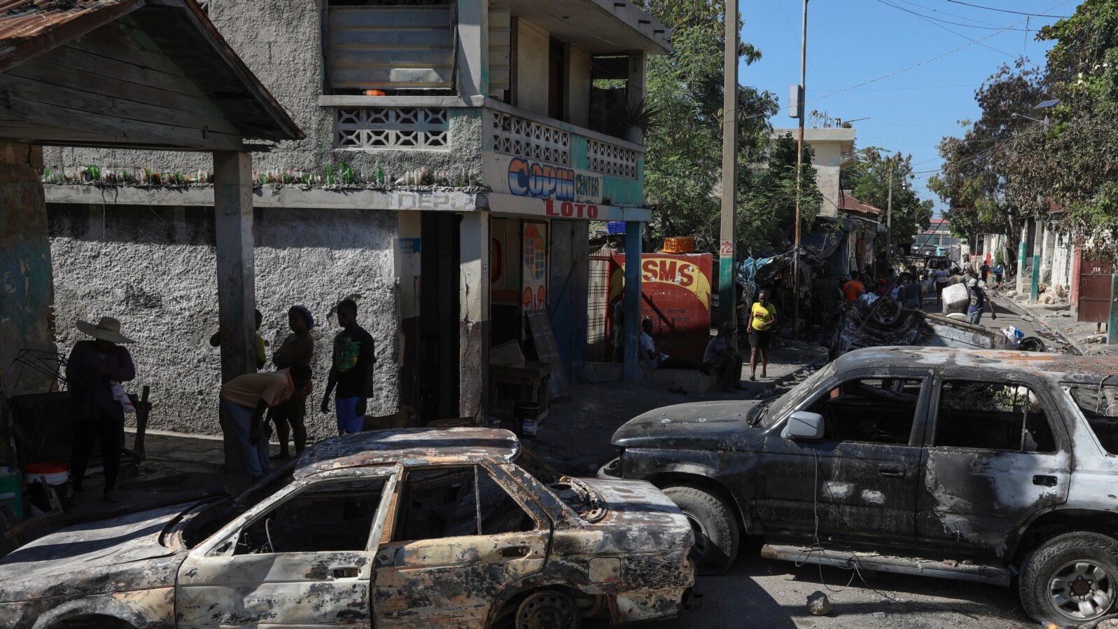 Residents walk past cars set on fire by armed gangs in the Poste Marchand neighborhood of Port-au-Prince, Haiti, Dec. 10, 2024. 