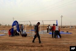 FILE - Workers set up a camp for displaced Iraqis in Khazer, Iraq, Oct. 19, 2016. More than 25,000 troops have mobilized for the fight to free Mosul, Iraq's second largest city and the largest urban area controlled by the Islamic State militants.