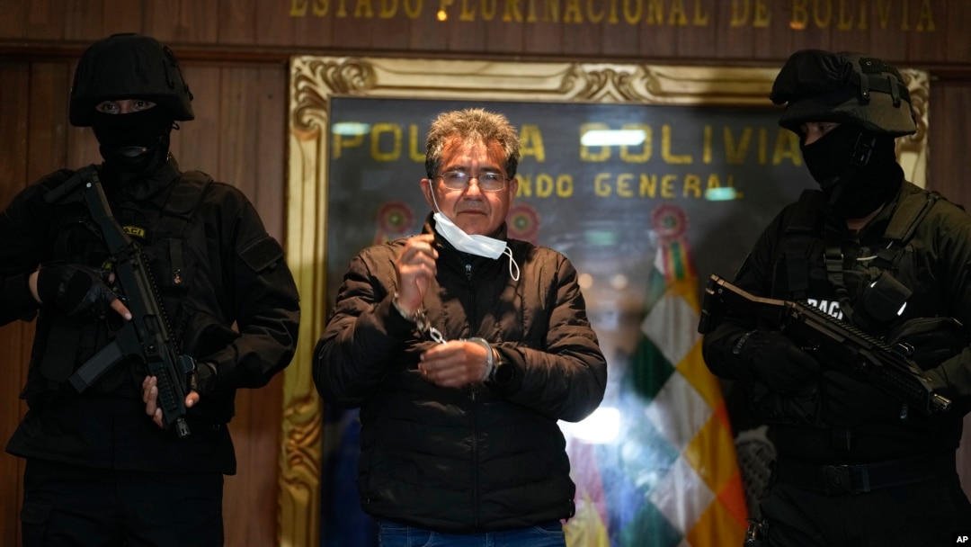 ARCHIVO - La policía escolta al ex coronel de policía Maximiliano Dávila, centro, mientras fue presentado a los medios en una oficina del Comando de la Policía Boliviana en La Paz, Bolivia, el 23 de enero de 2022. AP