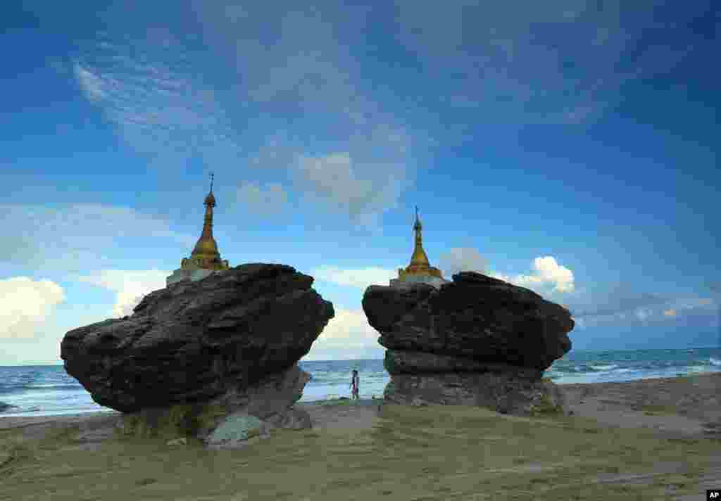 Two men walk past pagodas at Ngwe Saung beach, Pathein township, about 145 miles from Yangon, Myanmar.