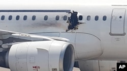 A gaping hole is visible in the side of a plane operated by Daallo Airlines as it sits on the runway of the airport in Mogadishu, Somalia, Feb. 2, 2016. 