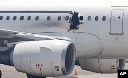 FILE - A gaping hole is visible in the side of a plane operated by Daallo Airlines as it sits on the runway of the airport in Mogadishu, Somalia, Feb. 2, 2016.