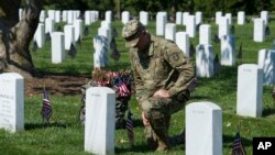 Un soldado de la tercera división del regimiento de infantería The Old Guard, honra a un soldado caído tras colocar banderas en las tumbas en el Cementerio Nacional de Arlington, Virginia, el jueves, 24 de mayo, de 2018.
