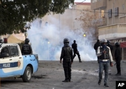 Police forces stand by tear gas during clashes in the city of Ennour, near Kasserine, Tunisia, Wednesday, Jan. 20, 2016.