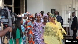 FILE - Some Chibok schoolgirls released by Boko Haram follow Minster of Women Affairs Aisha Alhassan after their visit to meet President Muhammadu Buhari In Abuja, Nigeria Oct. 19, 2016