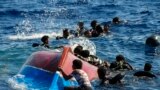 FILE - Migrants swim next to their overturned wooden boat during a rescue operation by Spanish NGO Open Arms at south of the Italian Lampedusa island at the Mediterranean sea, Aug. 11, 2022. 