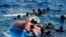 FILE - Migrants swim next to their overturned wooden boat during a rescue operation by Spanish NGO Open Arms at south of the Italian Lampedusa island at the Mediterranean sea, Aug. 11, 2022.