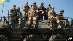 Ukraine's Prime Minister Arseniy Yatsenyuk, center, surrounded by U.S. and Ukrainian soldiers atop an armored personnel carrier in Lviv region, western Ukraine, June 3, 2015.