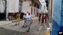U.S. tourists walks outside the Bodeguita del Medio Bar frequented by the late American novelist Ernest Hemingway in Old Havana, Cuba, May 24, 2015. One airline's cutback in flights to Cuba may be a sign that demand for travel to the island is slowing down amid uncertainty about Donald Trump's Cuba policies along with a near-doubling of Havana hotel prices and concerns over Zika.