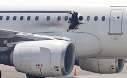 FILE - A gaping hole is visible in the side of a plane operated by Daallo Airlines as it sits on the runway of the airport in Mogadishu, Somalia, Feb. 2, 2016.