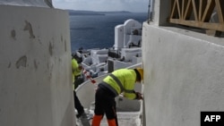 Municipal employees place caution tape to restrict access for tourists due to recent seismic activities in Oia village on the Greek island of Santorini, Feb. 5, 2025. 