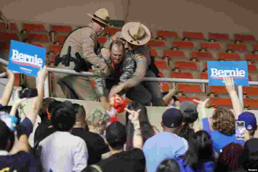 Supporters of U.S. Democratic presidential candidate Bernie Sanders react as law enforcement officers wrestle with a supporter of President Trump at a rally in Phoenix, Arizona.