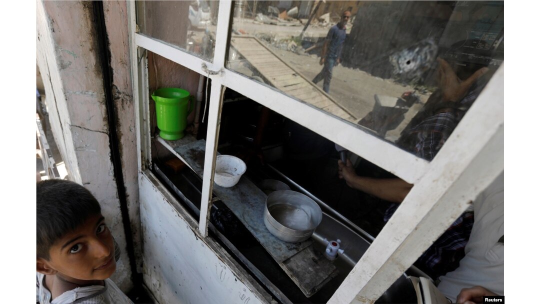 An Iraqi man is seen reflected in a cafe window in the destroyed Old City of Mosul, Iraq, Aug. 7, 2017.