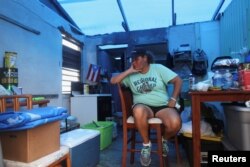 Jazmin Morales sits in her kitchen without power and with a plastic sheet replacing the roof in Yabucoa, Jan. 29, 2018.