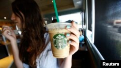 A patron holds an iced beverage at a Starbucks coffee store in Pasadena, Calif., July 25, 2013. Straws and stirrers are among the top 10 items found in coastal trash cleanups.