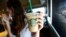 A patron holds an iced beverage at a Starbucks coffee store in Pasadena, Calif., July 25, 2013. Straws and stirrers are among the top 10 items found in coastal trash cleanups.