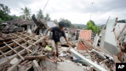 지난 11일 인도네시아 롬복섬에서 지진에 의해 무너진 집의 잔해 사이로 남성이 걷고 있다. 지난 5일 롬복섬에서 발생한 지진으로 지금까지 430여 명이 숨졌다. 