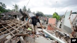 Seorang warga tengah berjalan di atas puing-puing reruntuhan bangunan pasca gempa di Lombok, 11 Agustus 2018. (Foto: dok).