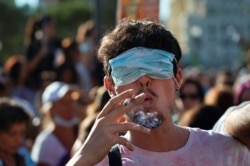 A man smokes a cigarette with his eyes covered by a face mask as he takes part in a protest against the use of protective masks amid the coronavirus pandemic, in Madrid, Spain, Aug. 16, 2020.