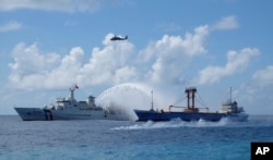 FILE - A Taiwan Coast Guard ship, left, and cargo ship take part in a search-and-rescue exercise off of Taiping island in the South China Sea, Nov. 29, 2016.