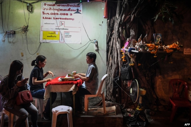 FILE - A fortune-teller, right, attends to a customer in Bangkok, Feb. 12, 2019.