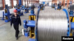 A worker walks past aluminium wires at a plant inside an industrial park in Binzhou, Shandong province, China, April 7, 2018. 