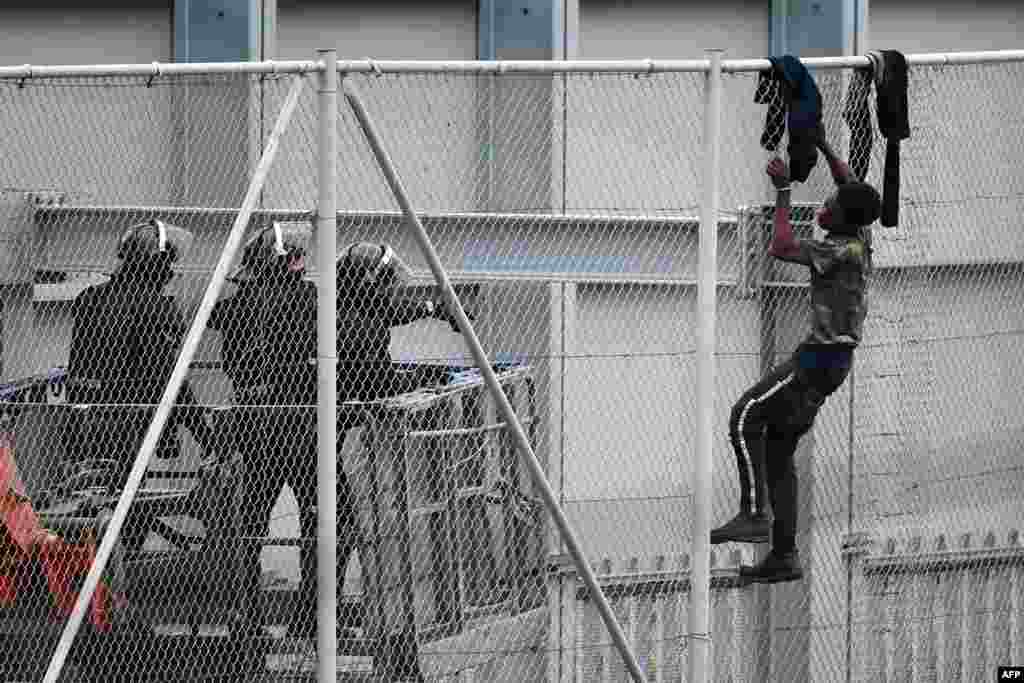 A youth tries to climb over the border fence in the Spanish exclave of Ceuta bordering Morocco.