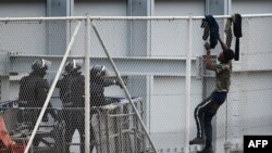 Seorang pemuda mencoba memanjat pagar pembatas di Ceuta, wilayah Spanyol yang berbatasan dengan Maroko, 13 April 2021. 