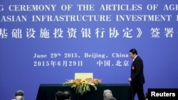 ລັດຖະມົນຕີການເງິນຈີນ ທ່ານ Lou Jiwei ຍ່າງຂຶ້ນເວທີ ໄປລົງນາມໃນຂໍ້ຕົກລົງຈັດຕັ້ງ ທະນາຄານ​ລົງທຶນ​ດ້ານ​​ພື້ນຖານ​ໂຄງ​ລ່າງຂອງ​ເອ​ເຊຍ ຫຼື AIIB ຢູ່ທີ່ສາລາປະຊາຊົນ ໃນປັກກິ່ງ, ວັນທີ 29 ມິຖຸນາ 2015.