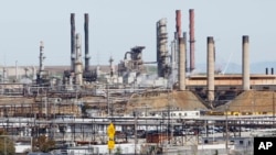 FILE - In this March 9, 2010, photo, a tanker truck passes an oil refinery in Richmond, California. 