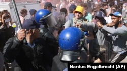 Protesting university students clash with riot police outside Parliament in Cape Town, South Africa