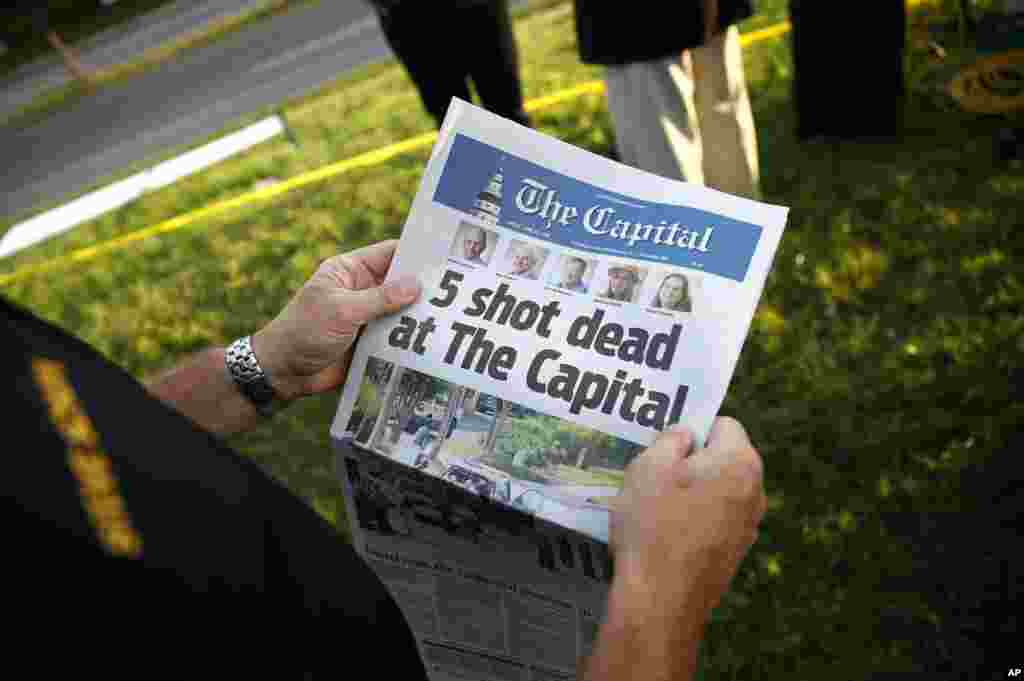 Merilend qraflığının rəsmisi Steve Schuh redaksiya heyəti qətıliama mruz qalmış qəzetin ofisi yaxınlığında əlində &quot;The Capital Gazette&quot; tutub. Annapolis, Merilend, ABŞ.