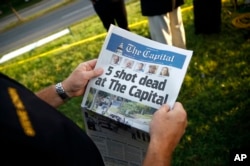 Steve Schuh, county executive of Anne Arundel County, holds a copy of The Capital Gazette near the scene of a shooting at the newspaper's office in Annapolis, Maryland. A man armed with smoke grenades and a shotgun attacked journalists in the building, June 28, 2018.