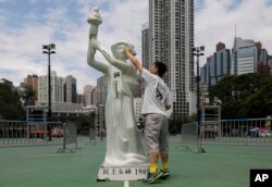 A man wipes the face of a statue of the Goddess of Democracy at Hong Kong's Victoria Park Monday, June 4, 2018.