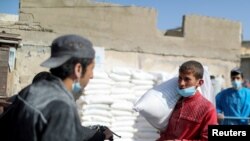 Seorang pekerja Palestina membawa sekantong tepung di luar pusat distribusi bantuan Badan Bantuan dan Pekerjaan PBB (UNRWA), di kamp pengungsi Pantai di Kota Gaza 7 April 2021. (REUTERS / Mohammed Salem)