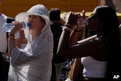 Tourists sip cold water as they shelter from a hot sunny afternoon near the Rome's Colosseum, Wednesday, July 5, 2023. According to weather forecasts temperatures are expected to rise on the upcoming week end reaching in some part of the country 45 Celsius degrees. (AP Photo/Gregorio Borgia)