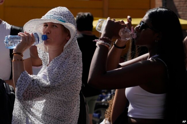 Tourists sip cold water as they shelter from a hot sunny afternoon near the Rome's Colosseum, Wednesday, July 5, 2023. According to weather forecasts temperatures are expected to rise on the upcoming week end reaching in some part of the country 45 Celsius degrees. (AP Photo/Gregorio Borgia)