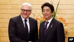 Menlu Jerman Frank-Walter Steinmeier (kiri) berpose dengan PM Jepang Shinzo Abe seusai rapat di Tokyo (11/4).