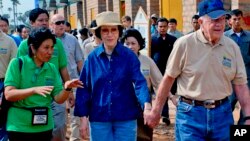 In this photo taken November 21, 2009 released by Habitat for Humanity, former U.S. President Jimmy Carter, right, holds the hand of his wife Rosalynn as they visit the Damnak Thom village where Habitat for Humanity volunteers built 21 houses.