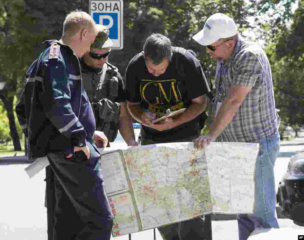 Ukrainian emergencies ministry officer, left, Donetsk People&#39;s Republic fighter, 2nd left, and members of the OSCE mission in Ukraine examine a map as they discuss the situation around the site of crashed Malaysia Airlines MH17, in the city of Donetsk, July 27, 2014.