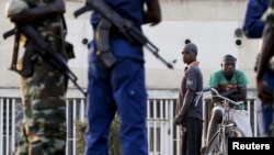 FILE - Residents look on as police and soldiers guard a voting station in Burundi's capital Bujumbura during the country's presidential elections, July 21, 2015.