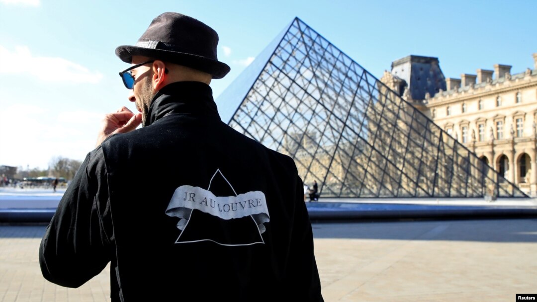French artist JR works in the courtyard of the Louvre Museum near the glass pyramid designed by Ieoh Ming Pei as the Louvre Museum celebrates the 30th anniversary of its glass pyramid in Paris, France, March 26, 2019. 