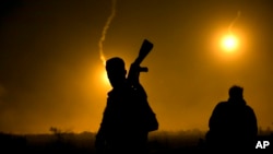 A U.S.-backed Syrian Democratic Forces (SDF) fighter watches illumination rounds light up Baghuz, Syria, as the last pocket of Islamic State militants is attacked on March 12, 2019. 