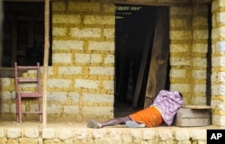 FILE - A man suffering from the Ebola virus lies on the floor outside a house in Port Loko Community, situated on the outskirts of Freetown, in Sierra Leone, Oct. 21, 2014.