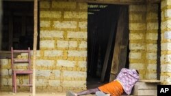 FILE - A man suffering from the Ebola virus lies on the floor outside a house in Port Loko Community, situated on the outskirts of Freetown, in Sierra Leone, Oct. 21, 2014. 