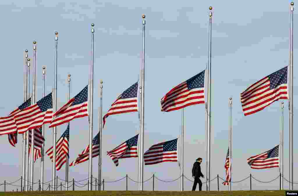 Mulher caminha entre as bandeiras americanas a meio mastro, em respeito às vítimas dos ataques em Paris, no Monumento de Washington no National Mall, em DC.&nbsp;