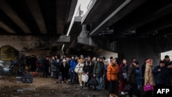 Люди чекають на евакуацію під зруйнованим мостом в місті Ірпінь біля Києва, 7 березня 2022 року. (Фото Dimitar DILKOFF / AFP)