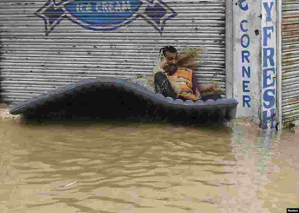 인도 싱가르에서 폭우로 홍수가 발생한 가운데, 한 주민이 간이보트를 타고 안전한 곳을 찾고 있다. 인도와 파키스탄에 내린 폭우로 수백명이 숨졌다.