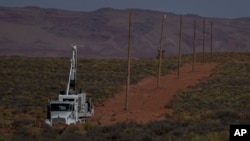 A crew with the Navajo Tribal Utility Authority installs power poles, Oct. 9, 2024, on the Navajo Nation in Halchita, Utah. 