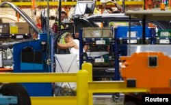 FILE - Production line workers fit parts to a Jeep Cherokee on the line at the upgraded North section of the Chrysler Toledo Assembly Complex, July 18, 2013.